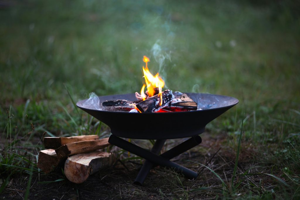 The flame of the fire burns in a metal fire bowl - warm your hands by the fire